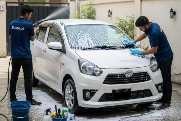 Two Bulao.pk technicians detailing a white Daihatsu Mira in Karachi, applying foam and wiping the bonnet, highlighting a clean and well-maintained compact hatchback