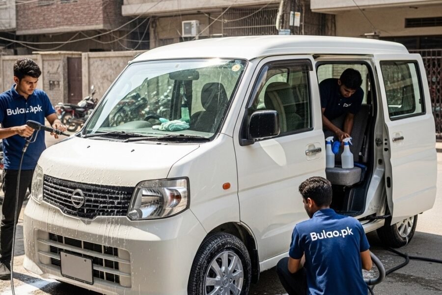 White Nissan Clipper compact van being professionally detailed by Bulao.pk technicians in navy blue t-shirts with 'Bulao.pk' on them. Technicians are cleaning the exterior, wheels, and interior in a Karachi street setting, showcasing a clean, polished, and hygienic van