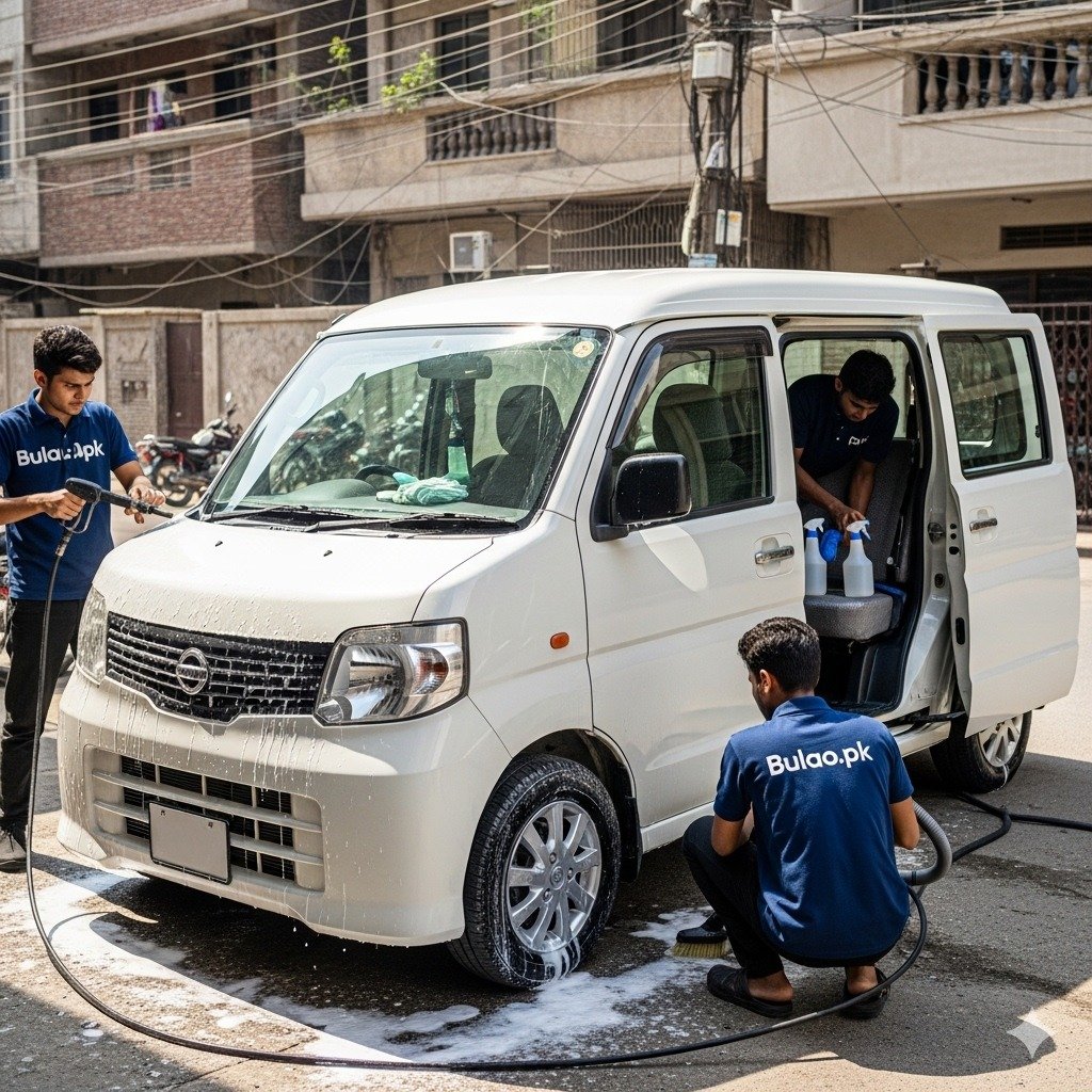 White Nissan Clipper compact van being professionally detailed by Bulao.pk technicians in navy blue t-shirts with 'Bulao.pk' on them. Technicians are cleaning the exterior, wheels, and interior in a Karachi street setting, showcasing a clean, polished, and hygienic van