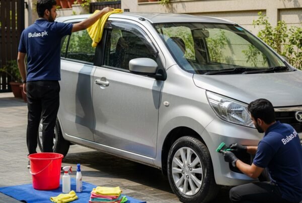 Two Bulao.pk technicians detailing a silver Daihatsu Move in Karachi, cleaning the roof and wheels with professional tools, showcasing a fresh, shiny, and well-maintained compact MPV."