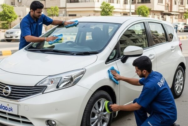 Hyper-realistic image of a white Nissan Note compact hatchback being cleaned by two Bulao.pk technicians on a Karachi street. One polishes the hood and doors while the other cleans the wheels.